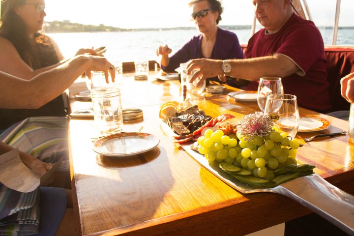 a group of people sitting at a table with food and water