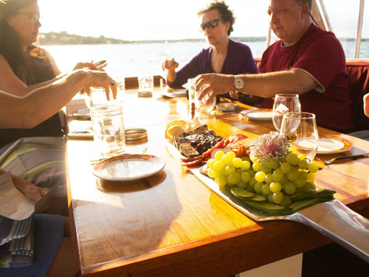 a group of people sitting at a table with food and water