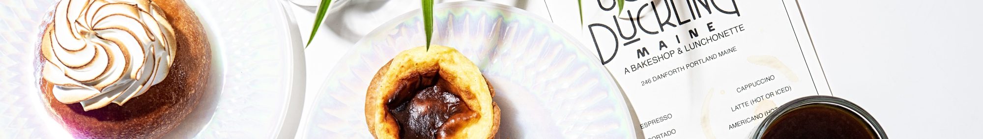 Assorted pastries and coffee with a menu on a white table.